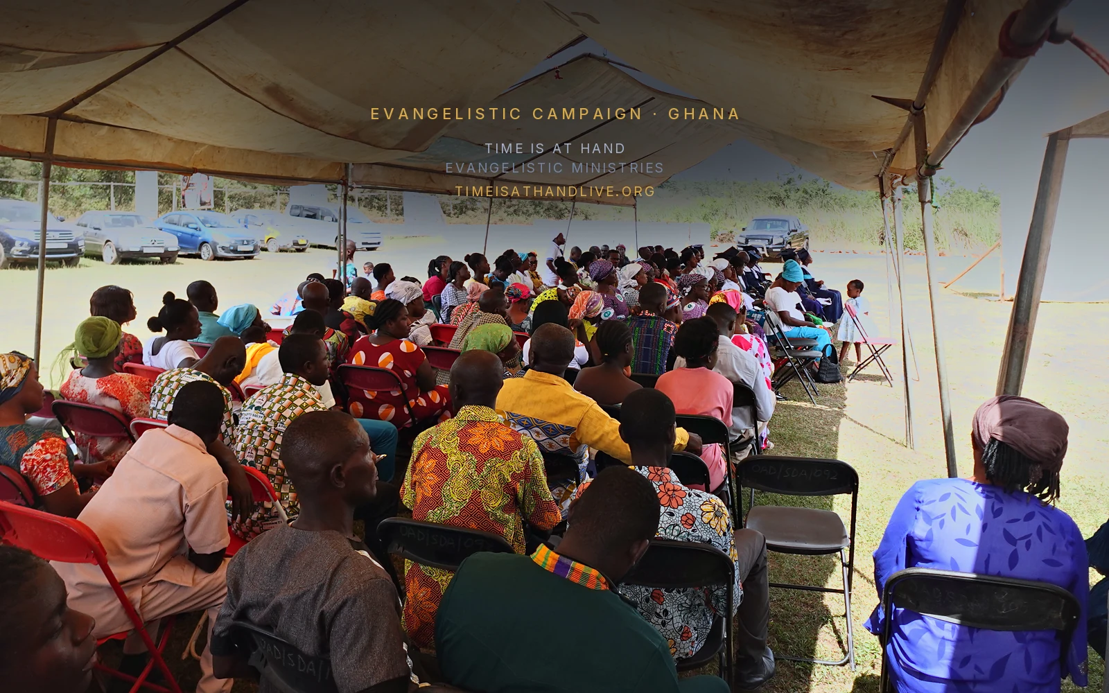 The congregation seated in rows under the tent
