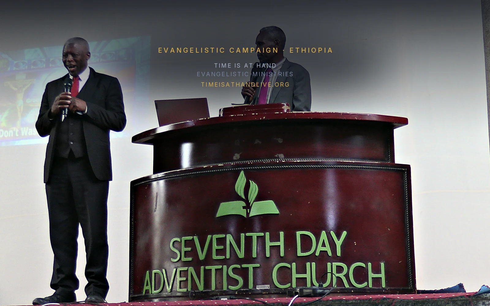 Two speakers together at the pulpit, the congregation seated before them